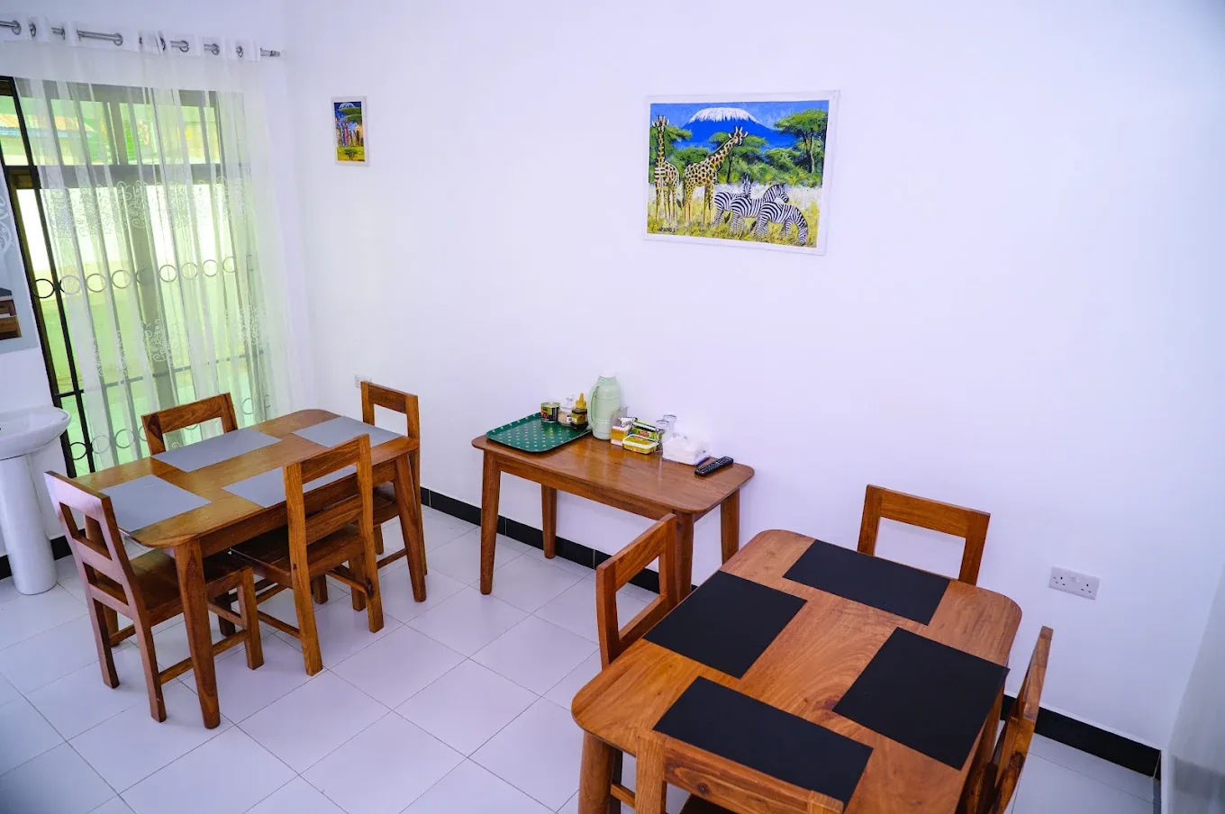 Breakfast room with wooden tables and a Tanzanian painting